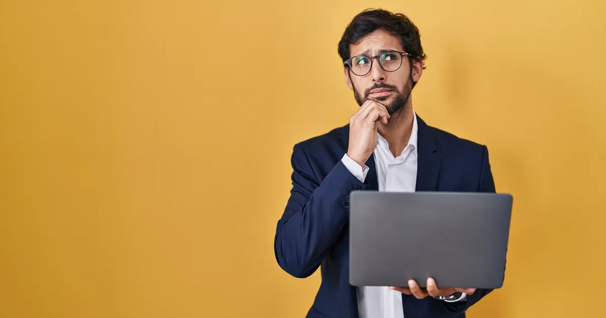 Man with an inquisitive facial expression holding a laptop computer