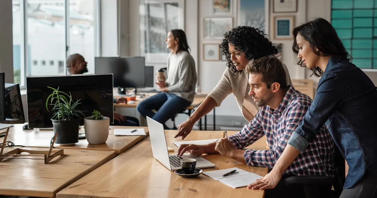 Three co-workers looking at a computer together.